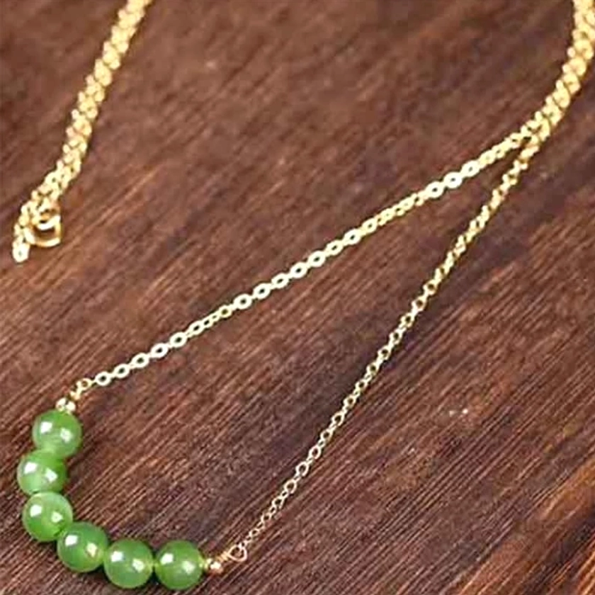 Overhead flat lay of jade beaded luck necklace showing seven polished cyan jade beads in curved pendant formation with gold lobster clasp and extended chain length - jade necklace full closure view