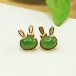 Hetian cyan jade rabbit stud earrings in sterling silver, front flat view showing cute bunny design with polished green jade stone