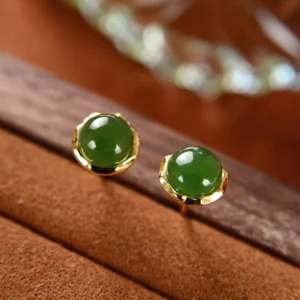 Hetian cyan jade stud earrings with gold-plated setting displayed on brown velvet, showing intricate floral bezel design and natural jade beads