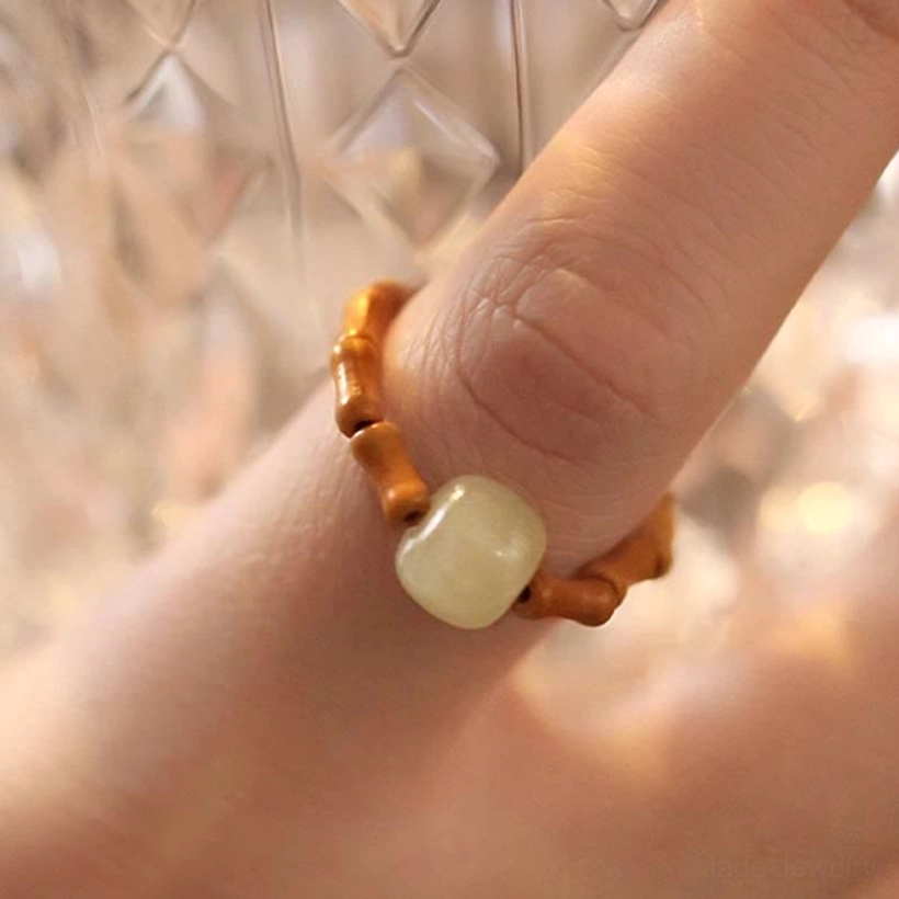 Detailed close-up front view of hetian jade bamboo ring showing oblate-shaped natural jade bead behind glass