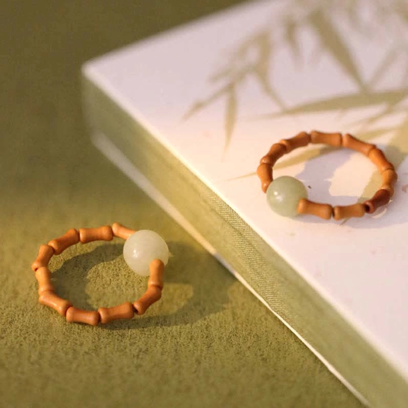 High overhead display of hetian jade bamboo prosperity ring on green fabric and bamboo-leaf printed book