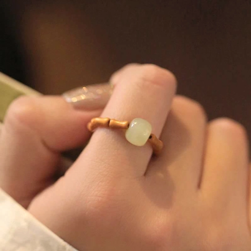 Side close-up of hetian jade bamboo ring worn on hand showing matte translucent light green jade bead