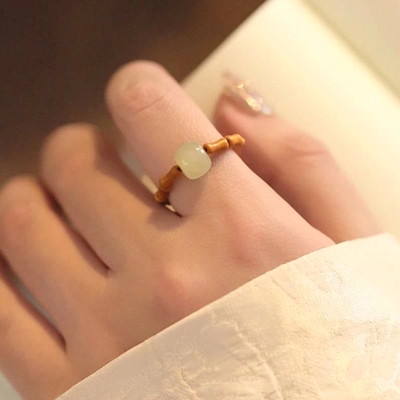 Hetian jade bamboo ring worn on finger with traditional han-style clothing sleeve showing authentic wear