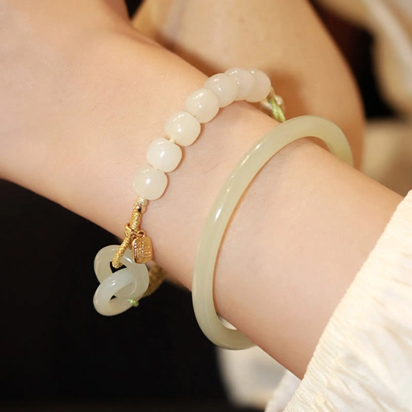 Hetian jade bangle and cord bracelet wrist close-up with round jade beads and gold charm