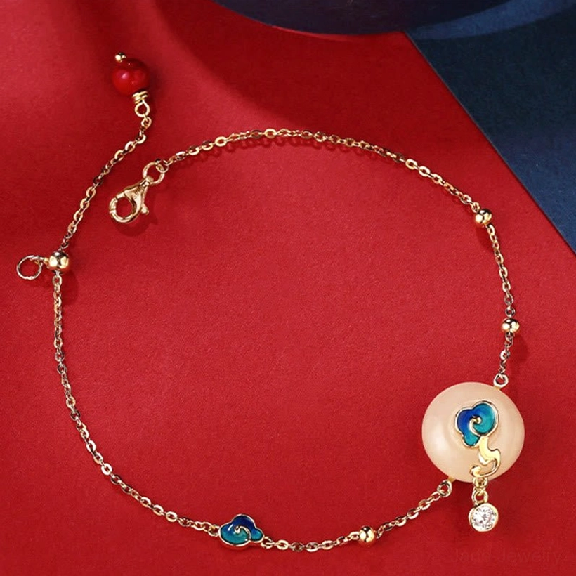 Hetian jade bracelet flat lay showing silver chain with round jade pendant and decorative blue enamel cloud charm with CZ accent
