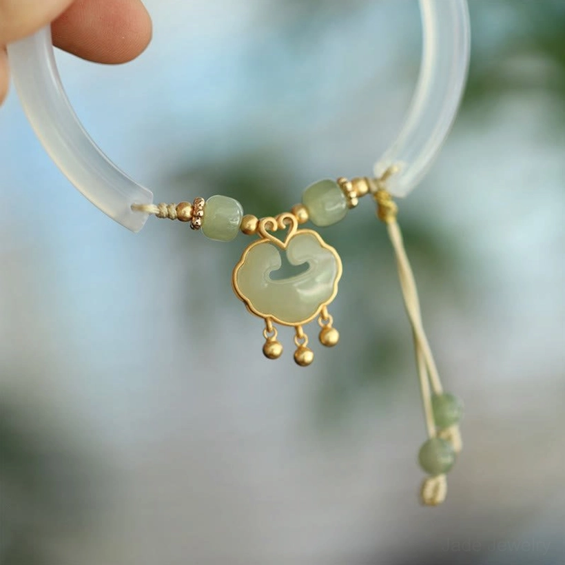 Close-up side view of hetian jade ruyi lock bracelet with polished sterling silver hardware and round jade beads, outdoor background