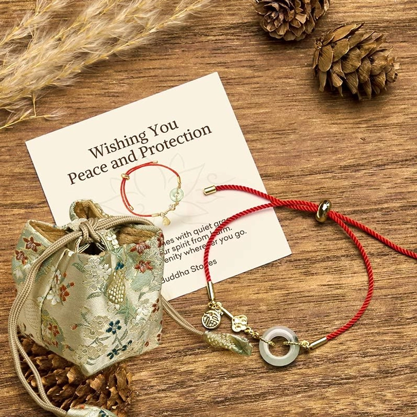 Red cord jade bracelet with deluxe embroidered gift bag and greeting card on wooden table with natural elements