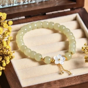Sterling silver hetian jade bracelet displayed in wooden jewelry box with shell flower charm and dried flowers