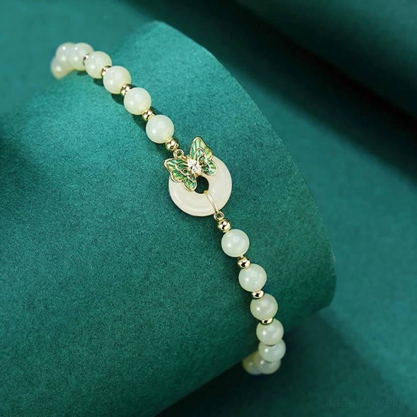 Sterling silver jade peace buckle bracelet displayed on green velvet cylinder - side angle view with elastic band detail