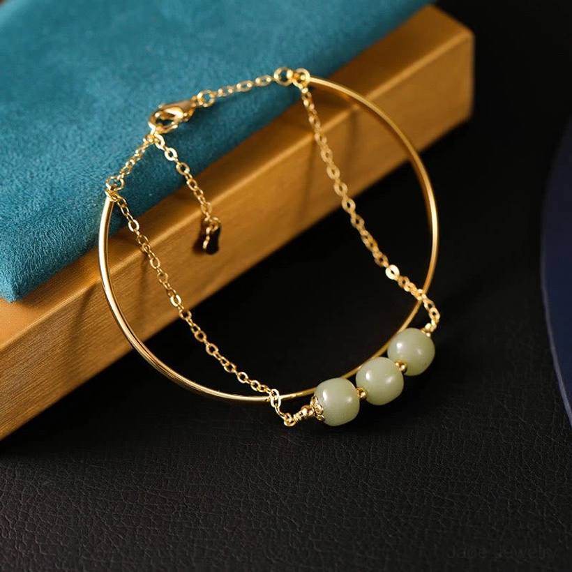 Hetian jade double layer bangle bracelet showing three light green beads with lobster claw clasp on blue velvet pad