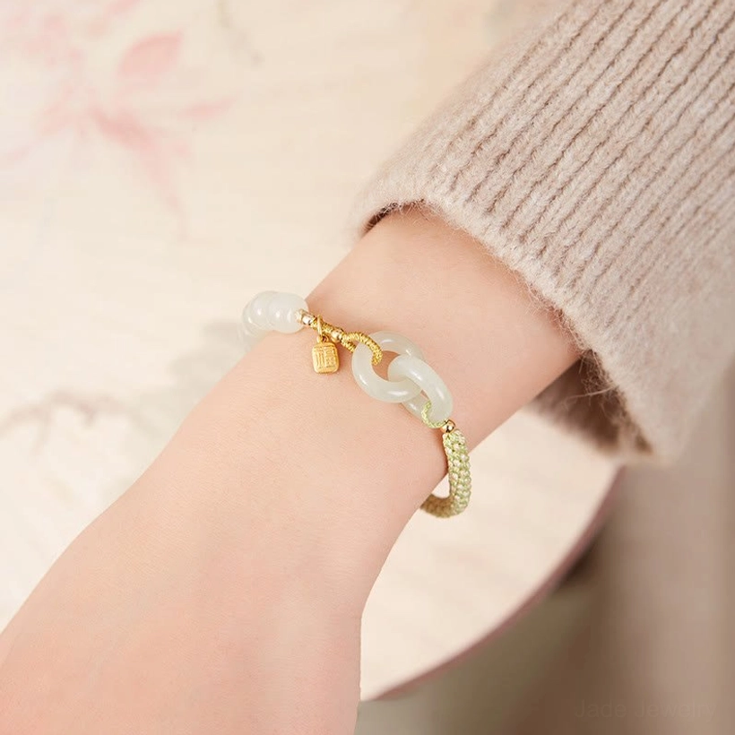 Hetian jade double peace buckle bracelet worn on wrist with green cord and gold charm detail