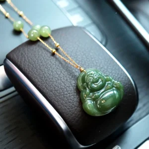 Polished Maitreya Buddha jade pendant with gold accents placed on car leather interior detail
