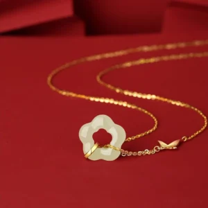 Delicate gold chain coiled with tiny butterfly charm and hollow Hetian jade flower pendant