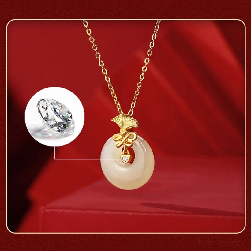 Close-up detail of hetian jade pendant with inlaid cubic zirconia sparkle and gold ginkgo mount