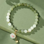 Hetian jade cat paw heart bracelet with ombre green and white jade beads, gold metal charm on solid background