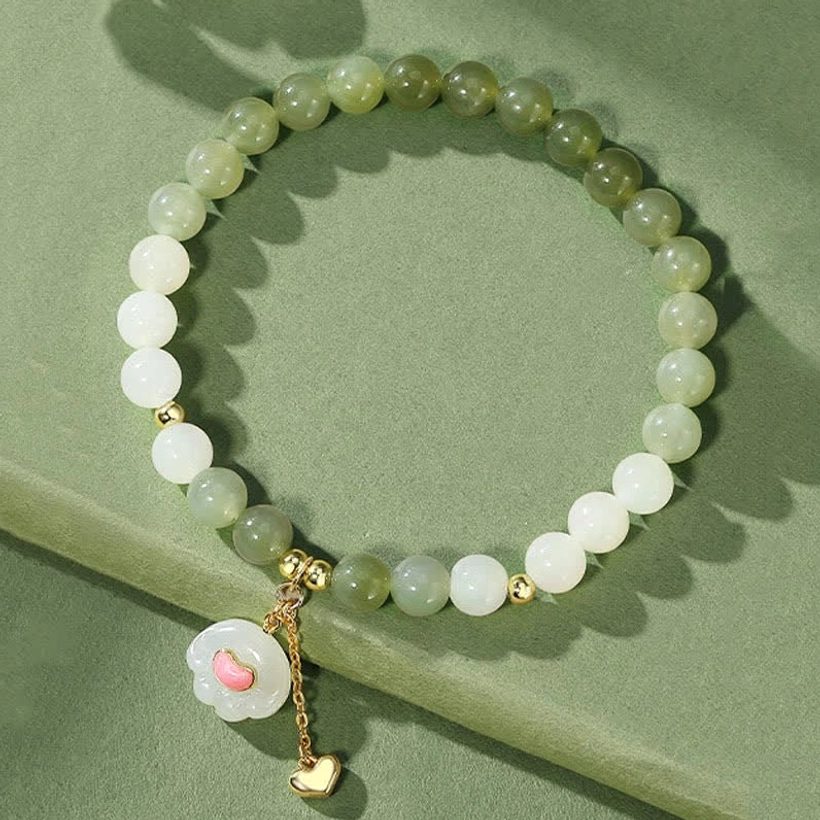 Hetian jade cat paw heart bracelet with ombre green and white jade beads, gold metal charm on solid background
