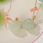 Hetian white jade cat paw pendant necklace flat lay with oriental plate and maple leaf decoration showing multiple pendant designs