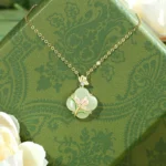 Four leaf clover Hetian jade pendant necklace with magnolia butterfly design in 925 sterling silver with 14k gold plating on gift box background