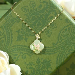 Four leaf clover Hetian jade pendant necklace with magnolia butterfly design in 925 sterling silver with 14k gold plating on gift box background