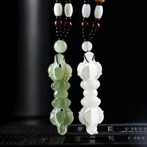 White and cyan Hetian jade Dorje Vajra pendants displayed upright on studio stand with accent beads