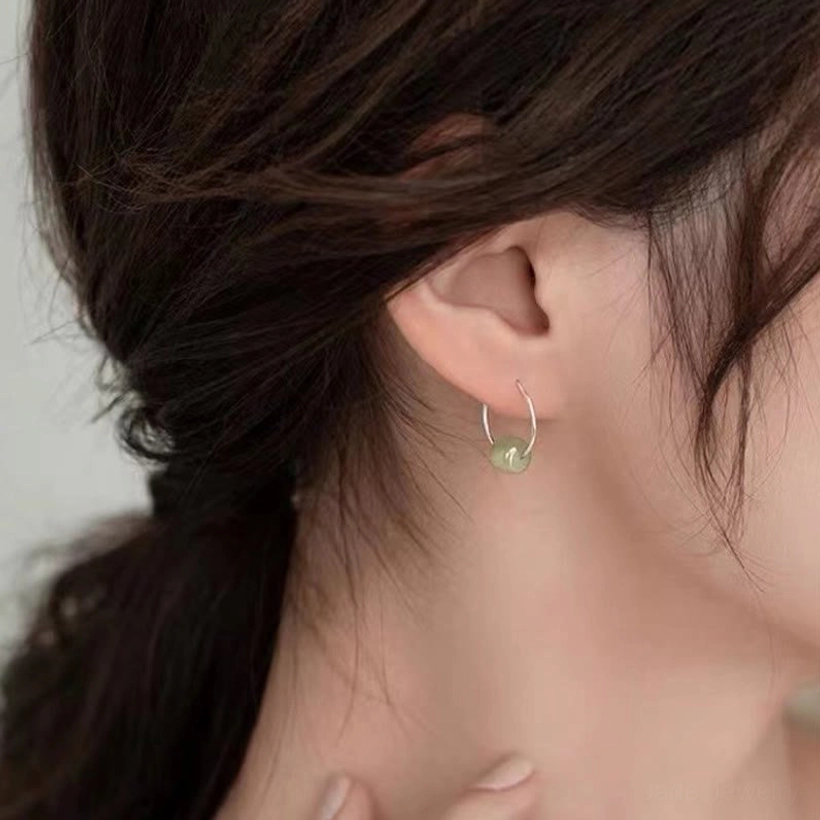 Hetian jade bead earrings collection view - assorted jade variety options in green white and cyan on wooden display with fabric backdrop
