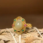 Hetian jade egg hollow filigree ring with gold-plated copper band, front overhead view showing intricate carved pattern and oval jade center stone