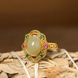 Hetian jade egg hollow filigree ring with gold-plated copper band, front overhead view showing intricate carved pattern and oval jade center stone