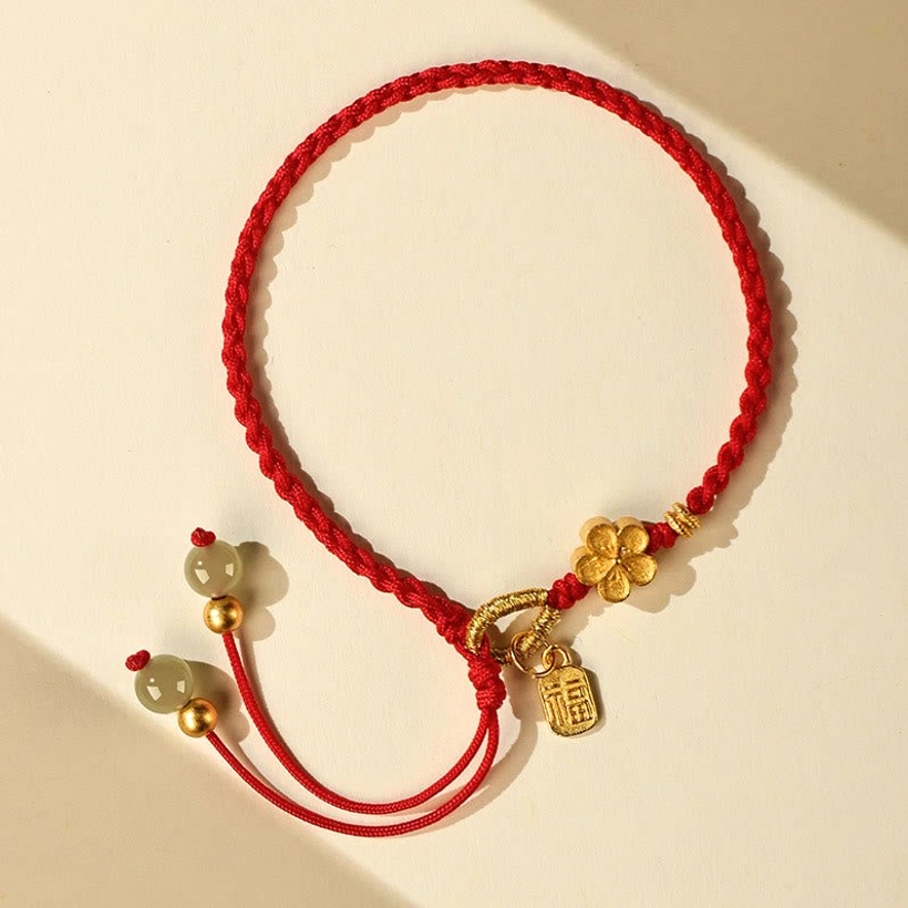 Hetian jade fu character bracelet front flat lay displaying red braided cord with jade beads and alloy charms