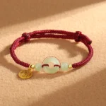 Hetian jade peace buckle fu character charm bracelet with red braided cord and 925 sterling silver pendant on brown fabric