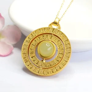 Hetian jade rotatable Fu pendant necklace overhead view on ceramic plate with pink petals, featuring carved gold blessing frame and light green jade stone