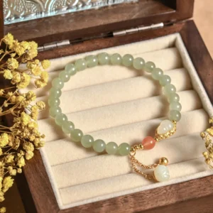 Hetian jade gourd lotus bracelet with sterling silver charm on wooden jewelry tray with dried flowers and aesthetic styling