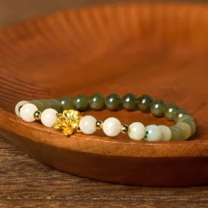 Premium Hetian jade lotus beaded bracelet featuring smooth ombre gradient jade beads with shiny gold lotus ornament, three-quarter angle view