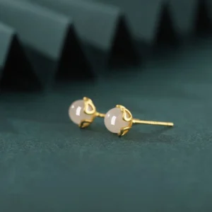 Side oblique view of jade heart stud earrings displaying the metal setting and earring post design against grey geometric backdrop