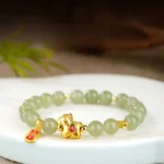 Hetian jade horse zodiac bracelet flat lay showing light green jade beads with gold horse charm and red fortune pendant on wooden tray
