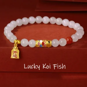 Hetian white jade koi fish lucky bracelet with red agate and 925 sterling silver charm on red velvet background, top-down flat lay view
