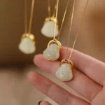 Hetian jade laughing Buddha pendant necklace overhead view with thin gold chain and polished white jade Buddha charm