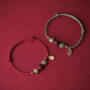 Two mixed color jade luck bracelets with red and green cords, matching cinnabar lotus charms and gold hardware