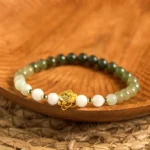 Natural Hetian jade gradient lotus bracelet with ombre green to white jade beads and gold lotus charm, top-down flat lay view
