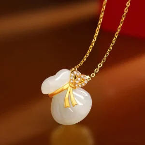Hetian white jade money bag necklace pendant with gold-plated bowknot and cubic zirconia detail, close-up on warm background