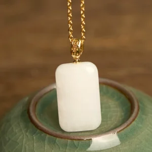 White jade pendant necklace angled view showing smooth polished stone and gold-toned metal hardware detail