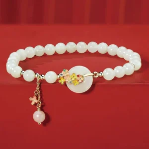 Hetian jade osmanthus peace buckle bracelet with zircon accents on red satin - flat lay overhead view