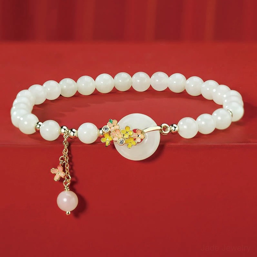 Hetian jade osmanthus peace buckle bracelet with zircon accents on red satin - flat lay overhead view