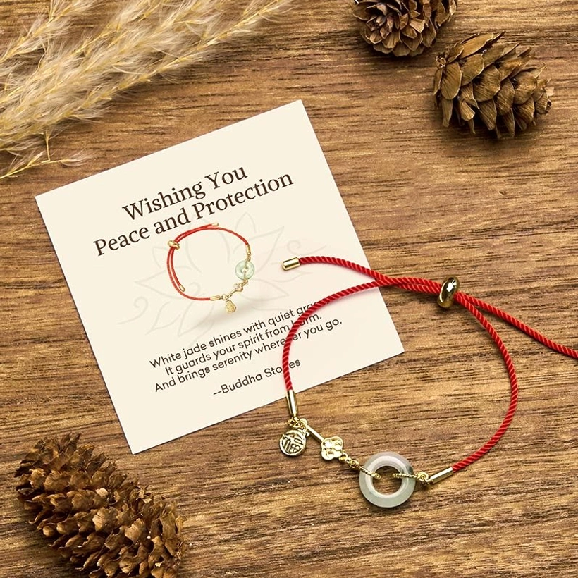 Hetian jade red string bracelet with Fu character displayed on wooden surface with greeting card and natural decorations