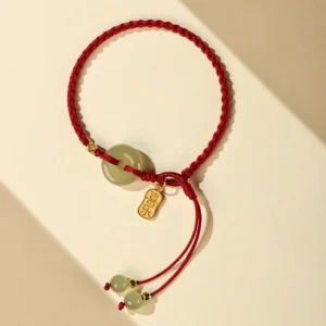 Natural hetian jade peace buckle bracelet angled top view with adjustable braided red string and gold ingot-shaped charm