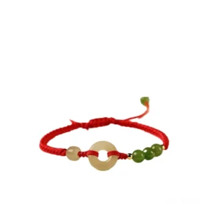 Flat lay view of Hetian jade peace buckle bracelet with red woven cord and jade beads on light beige background