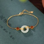 Hetian jade peace buckle bracelet with red agate and gold-plated silver clasp on Chinese calligraphy book