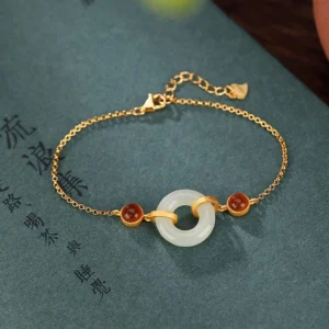 Hetian jade peace buckle bracelet with red agate and gold-plated silver clasp on Chinese calligraphy book