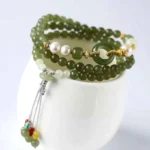 Hetian jade peace buckle bracelet with pearl accents on ceramic holder - three quarter view