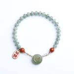 Hetian jade peace buckle bracelet with red agate beads and gold chain charm - flat lay top view