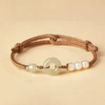 Hetian jade peace buckle bracelet with freshwater pearls and gold spacers on beige background
